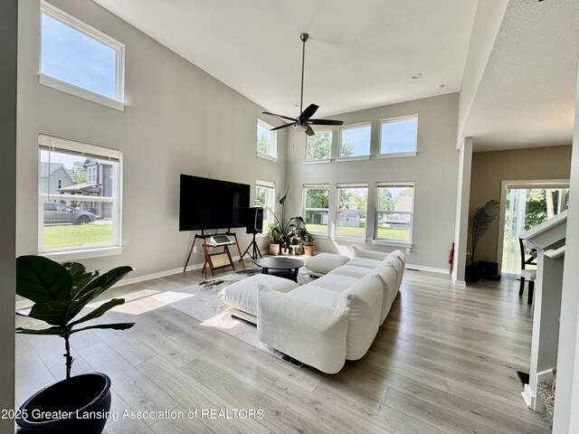 4314 Ringneck Ln, Holt, MI 48842 - living room featuring a ceiling fan, a towering ceiling, and light wood-style floors