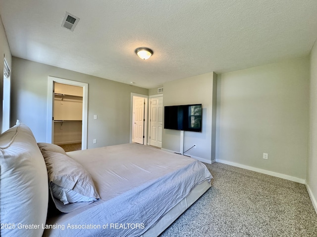 4314 Ringneck Ln, Holt, MI 48842 - carpeted bedroom featuring a walk in closet, a textured ceiling, and a closet