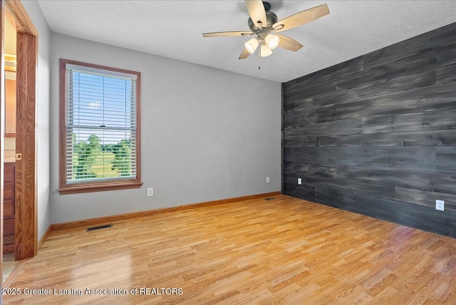 5159 E Pratt Rd, Saint Johns, MI 48879 - empty room featuring a ceiling fan, wood finished floors, and wooden walls