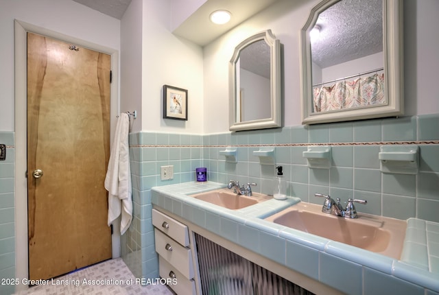 4451 Greenwood Dr, Okemos, MI 48864 - full bath featuring double vanity, tile walls, a textured ceiling, and wainscoting