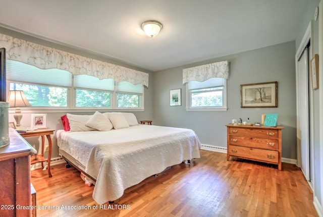 4451 Greenwood Dr, Okemos, MI 48864 - bedroom featuring multiple windows, light wood-style flooring, a closet, and a baseboard heating unit