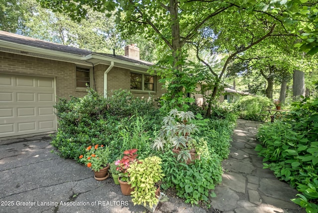 4451 Greenwood Dr, Okemos, MI 48864 - view of side of property featuring a chimney, brick siding, and a garage