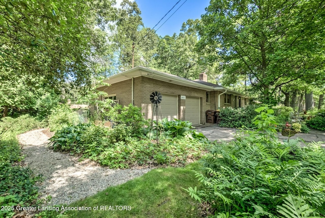4451 Greenwood Dr, Okemos, MI 48864 - view of home's exterior featuring a garage, a chimney, and brick siding