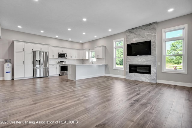 330 Vansickle Dr Unit 31, Charlotte, MI 48813 - unfurnished living room featuring light wood-style flooring, plenty of natural light, recessed lighting, and a high end fireplace