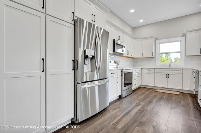 330 Vansickle Dr Unit 31, Charlotte, MI 48813 - kitchen featuring appliances with stainless steel finishes, decorative backsplash, wood finished floors, white cabinetry, and recessed lighting