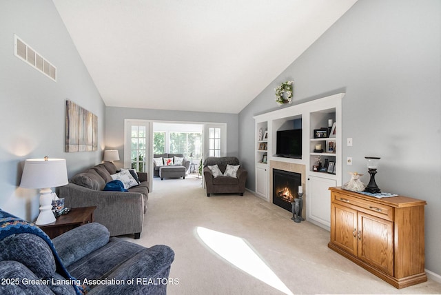 26 Aviemore Dr, Mason, MI 48854 - living area featuring high vaulted ceiling, a warm lit fireplace, light carpet, and built in shelves