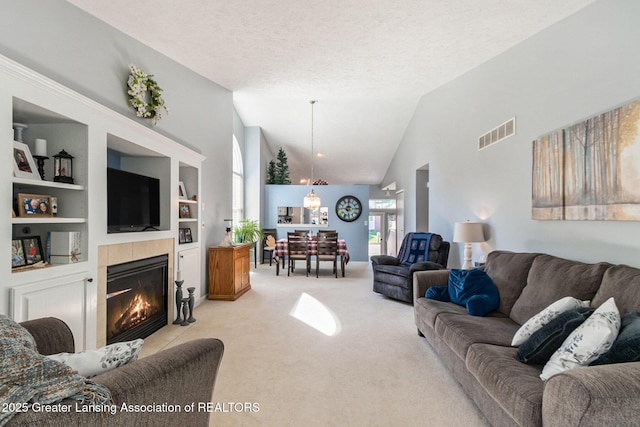 26 Aviemore Dr, Mason, MI 48854 - living area featuring light carpet, vaulted ceiling, a tiled fireplace, built in features, and a textured ceiling