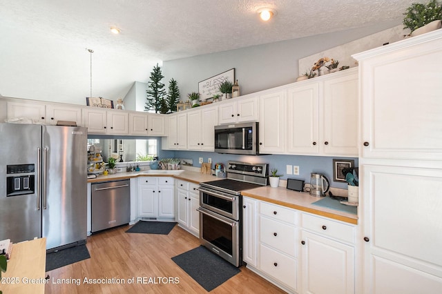 26 Aviemore Dr, Mason, MI 48854 - kitchen with appliances with stainless steel finishes, a textured ceiling, white cabinets, light countertops, and light wood-style flooring