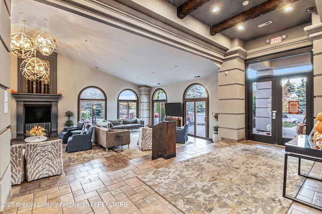 3706 Flying Gulch Dr, Holt, MI 48842 - living room featuring beam ceiling, a chandelier, stone tile flooring, a glass covered fireplace, and high vaulted ceiling