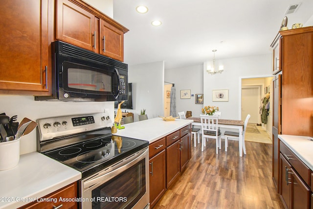 3706 Flying Gulch Dr, Holt, MI 48842 - kitchen featuring stainless steel electric range, black microwave, wood finished floors, a chandelier, and light countertops