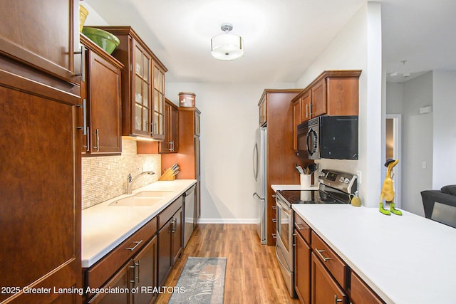 3706 Flying Gulch Dr, Holt, MI 48842 - kitchen with appliances with stainless steel finishes, wood finished floors, backsplash, glass insert cabinets, and light countertops