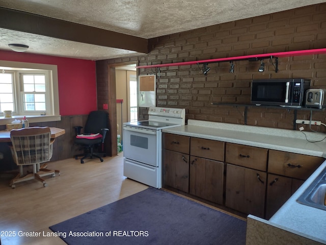 16711 Stark Rd, Springport, MI 49284 - kitchen featuring electric range, a textured ceiling, light wood-type flooring, light countertops, and wainscoting