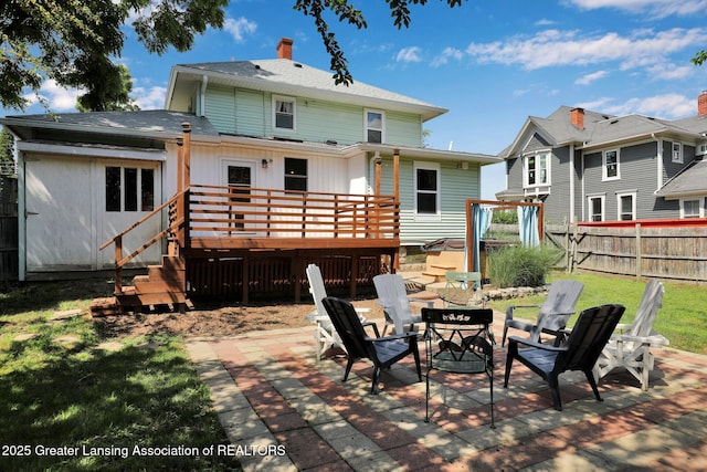 302 E State St, Saint Johns, MI 48879 - rear view of property featuring a wooden deck, a patio, an outdoor fire pit, a chimney, and board and batten siding