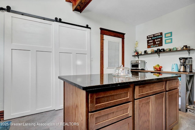 302 E State St, Saint Johns, MI 48879 - kitchen featuring dark stone counters, a barn door, open shelves, and a center island