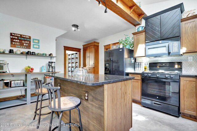 302 E State St, Saint Johns, MI 48879 - kitchen featuring black appliances, decorative backsplash, a center island, a breakfast bar, and finished concrete floors