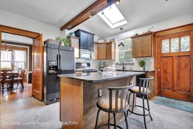 302 E State St, Saint Johns, MI 48879 - kitchen with black fridge, stove, a skylight, backsplash, and stainless steel microwave