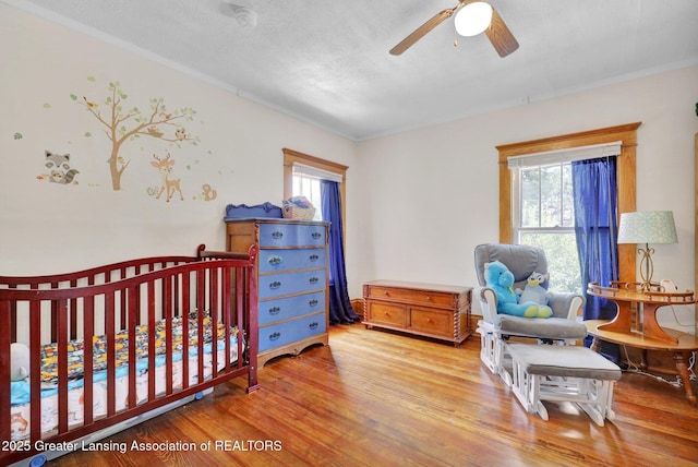 302 E State St, Saint Johns, MI 48879 - bedroom with multiple windows, light wood finished floors, ornamental molding, a nursery area, and a textured ceiling