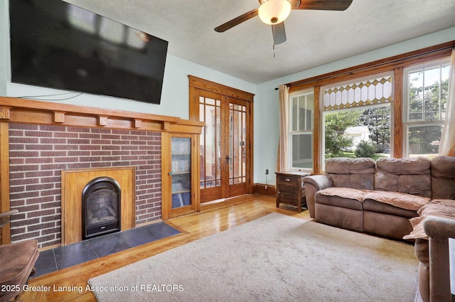 302 E State St, Saint Johns, MI 48879 - living area featuring ceiling fan, wood finished floors, a brick fireplace, and a textured ceiling