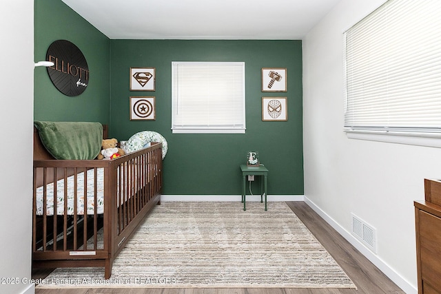 2818 Almar Ln, Lansing, MI 48910 - bedroom featuring a nursery area, multiple windows, and wood finished floors