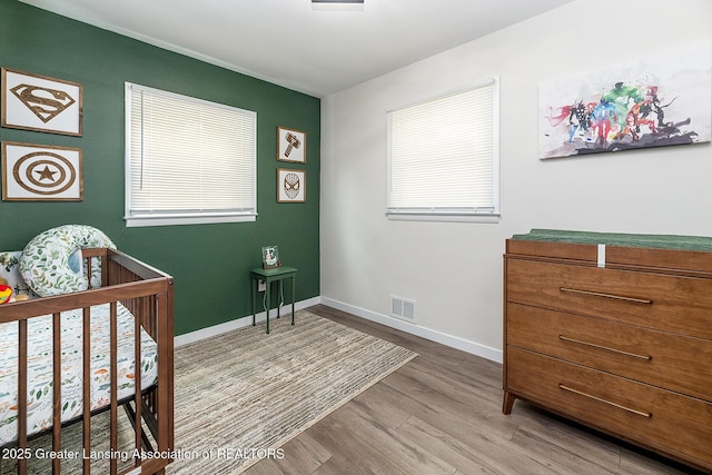 2818 Almar Ln, Lansing, MI 48910 - bedroom featuring wood finished floors, a nursery area, and multiple windows