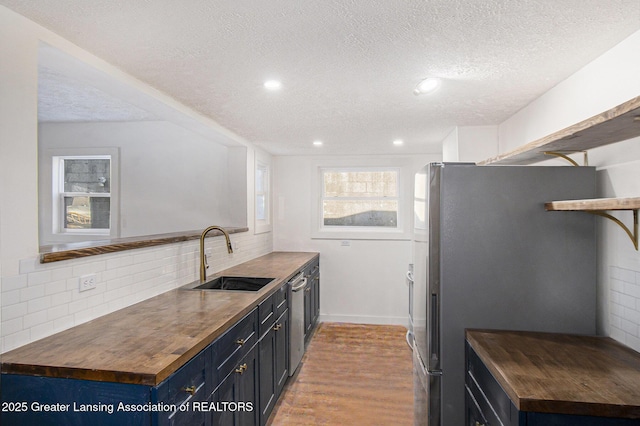 625 W Jefferson St, Grand Ledge, MI 48837 - kitchen featuring wood counters, stainless steel appliances, a textured ceiling, decorative backsplash, and light wood-style flooring