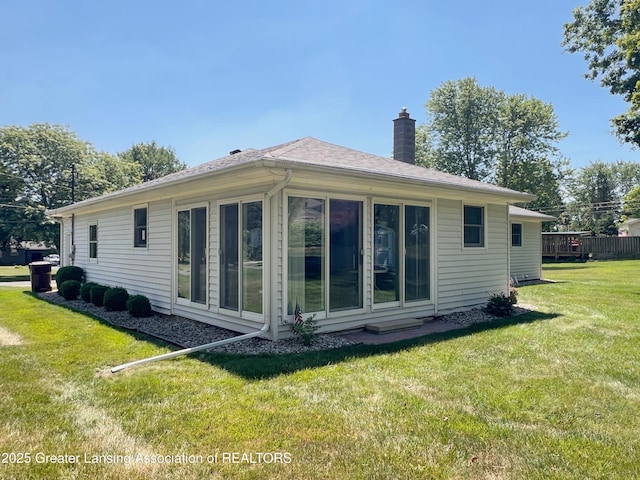 6716 Bunker Hill Dr, Lansing, MI 48906 - back of house featuring a chimney, a lawn, and a sunroom