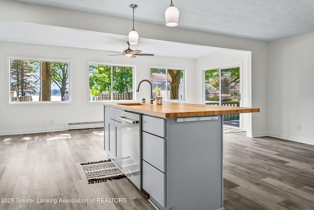 1337 Shepard St, Crystal, MI 48818 - kitchen with butcher block countertops, a baseboard heating unit, wood finished floors, and an island with sink