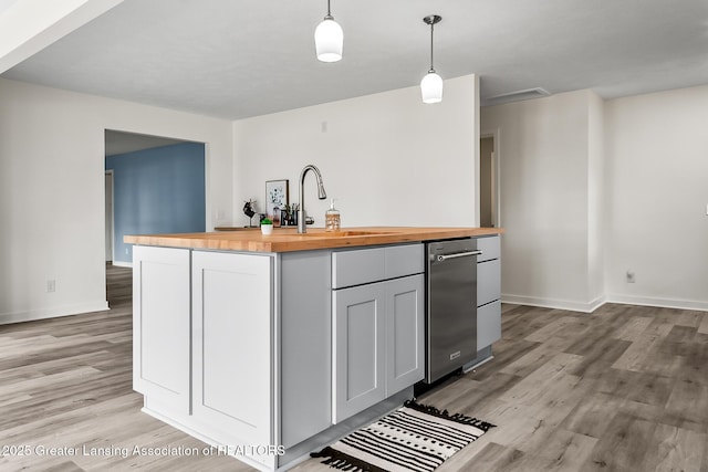 1337 Shepard St, Crystal, MI 48818 - kitchen with butcher block counters, light wood-style flooring, dishwasher, a kitchen island with sink, and pendant lighting