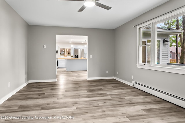 1337 Shepard St, Crystal, MI 48818 - unfurnished living room featuring a baseboard heating unit, a ceiling fan, and wood finished floors