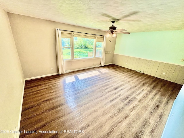 1214 Otto Rd Unit R1, Charlotte, MI 48813 - spare room with wood finished floors, a ceiling fan, a textured ceiling, and a wainscoted wall