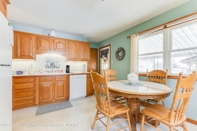 1220 Seymour St, Grand Ledge, MI 48837 - kitchen featuring white appliances, light countertops, light floors, and brown cabinetry