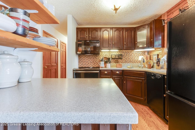 3536 N Royston Rd, Potterville, MI 48876 - kitchen with black appliances, light wood-style flooring, light countertops, backsplash, and glass insert cabinets