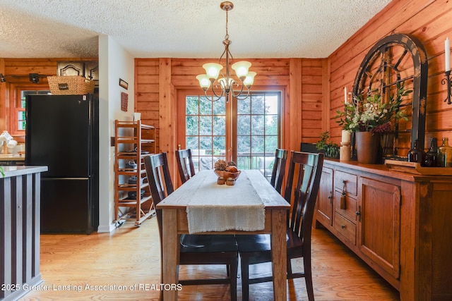 3536 N Royston Rd, Potterville, MI 48876 - dining area featuring light wood-style floors, a textured ceiling, and a chandelier