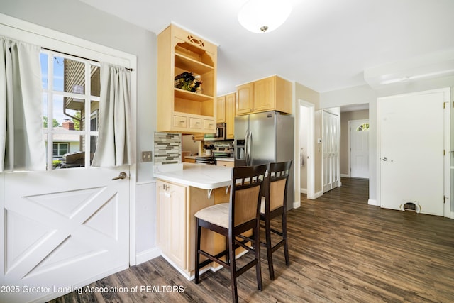 4629 Grandwoods Dr, Lansing, MI 48917 - kitchen featuring stainless steel appliances, light brown cabinetry, dark wood-style flooring, a breakfast bar area, and light countertops