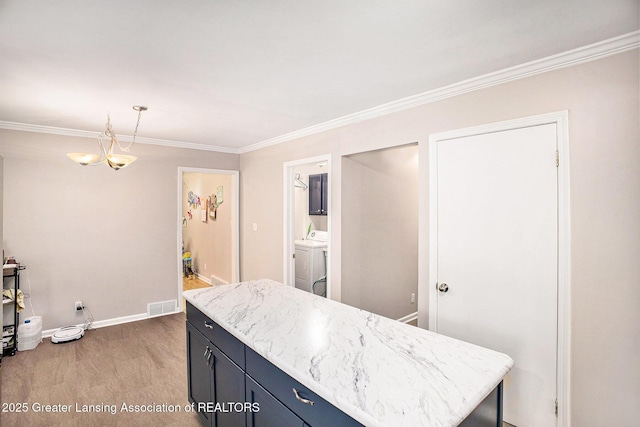 4326 Manitou Dr, Okemos, MI 48864 - kitchen with light wood-type flooring, crown molding, washer and dryer, hanging light fixtures, and light stone counters