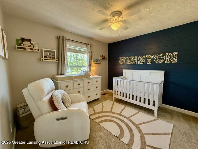 310 Brittany Ln, Mulliken, MI 48861 - bedroom with a nursery area, light carpet, an accent wall, a ceiling fan, and a textured ceiling