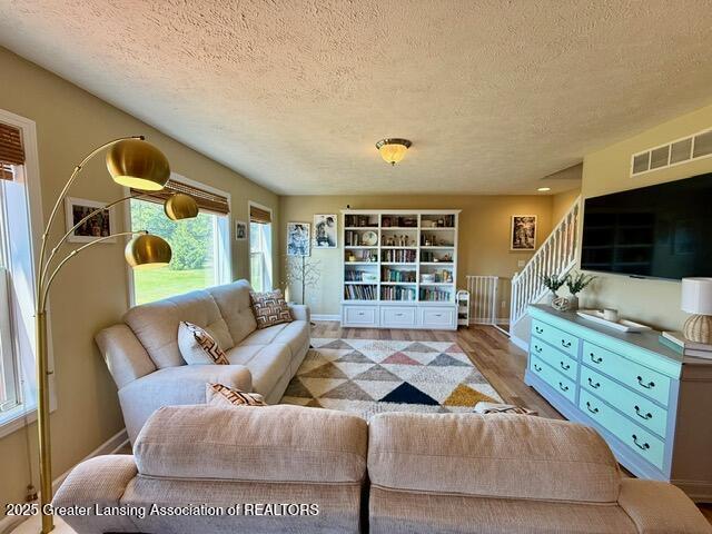 310 Brittany Ln, Mulliken, MI 48861 - living area with a textured ceiling, wood finished floors, and stairway