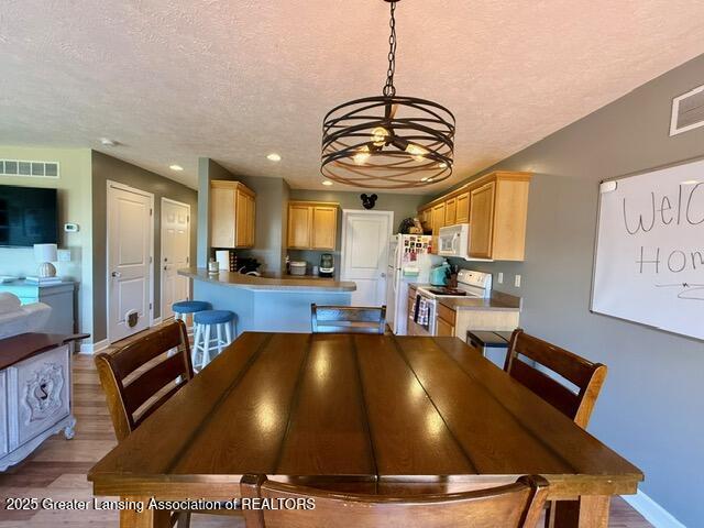 310 Brittany Ln, Mulliken, MI 48861 - dining room featuring a textured ceiling, light wood-style floors, a chandelier, and recessed lighting