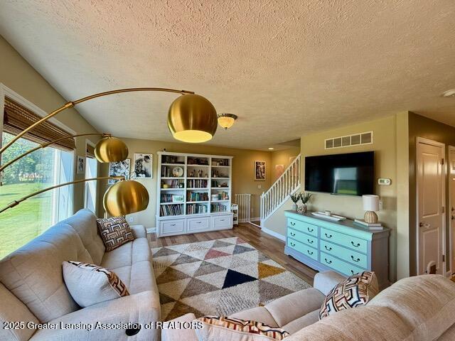 310 Brittany Ln, Mulliken, MI 48861 - living room with a textured ceiling, wood finished floors, and stairway