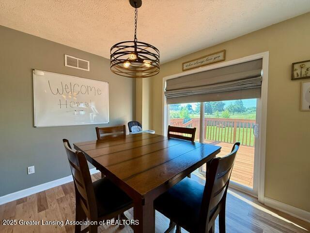 310 Brittany Ln, Mulliken, MI 48861 - dining space featuring wood finished floors, a chandelier, and a textured ceiling