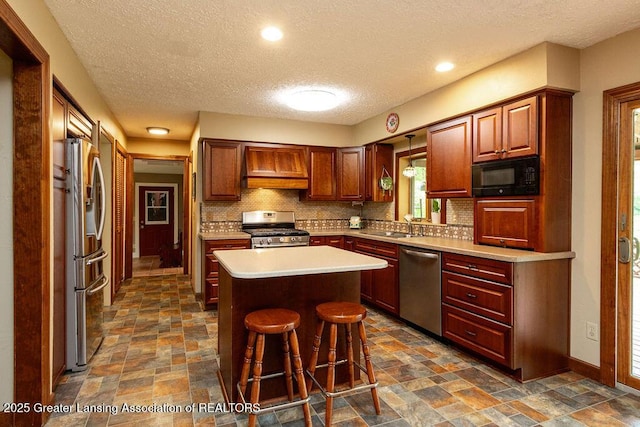 3536 Burkley Rd, Williamston, MI 48895 - kitchen with appliances with stainless steel finishes, a textured ceiling, dark stone finish flooring, a center island, and backsplash