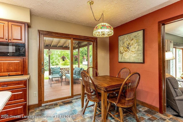 3536 Burkley Rd, Williamston, MI 48895 - dining area featuring stone finish floors, a textured ceiling, and a chandelier