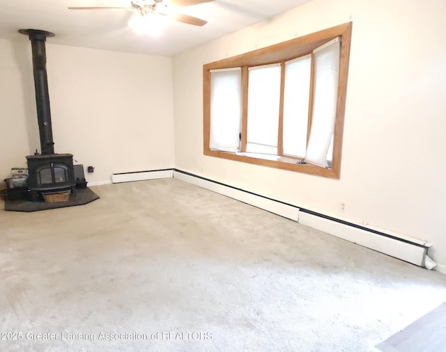 3612 Dell Rd, Holt, MI 48842 - unfurnished living room featuring ceiling fan, a wood stove, a baseboard radiator, and carpet