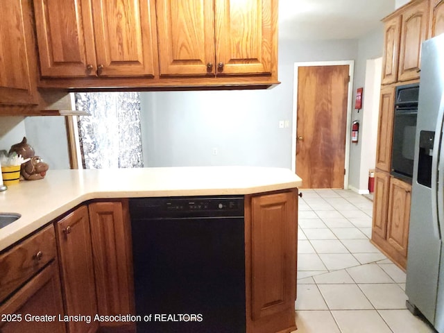 3612 Dell Rd, Holt, MI 48842 - kitchen with black appliances, light countertops, light tile patterned floors, and brown cabinetry