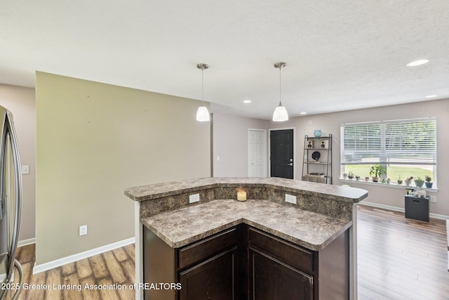 4930 N Campers Trl, Perrinton, MI 48871 - kitchen featuring wood finished floors, dark brown cabinets, a center island, pendant lighting, and recessed lighting