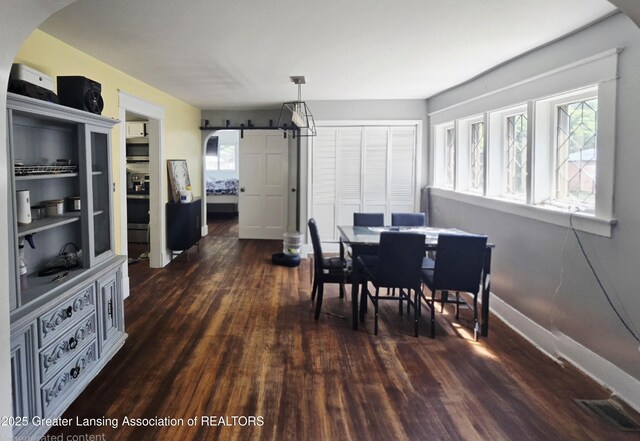 412 N Hickory St, Owosso, MI 48867 - dining room featuring dark wood-type flooring, arched walkways, and a barn door