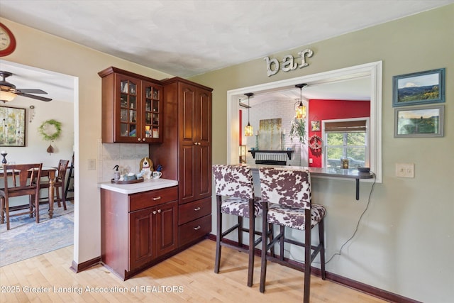 7050 E Eaton Hwy, Sunfield, MI 48890 - kitchen featuring light wood-style floors, glass insert cabinets, a ceiling fan, and tasteful backsplash