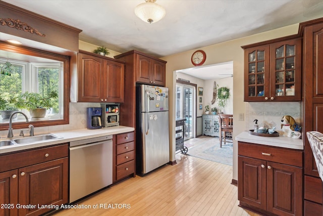 7050 E Eaton Hwy, Sunfield, MI 48890 - kitchen with appliances with stainless steel finishes, backsplash, light countertops, glass insert cabinets, and light wood-type flooring