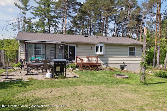 7050 E Eaton Hwy, Sunfield, MI 48890 - rear view of house featuring an outdoor fire pit, a deck, a sunroom, and a gate