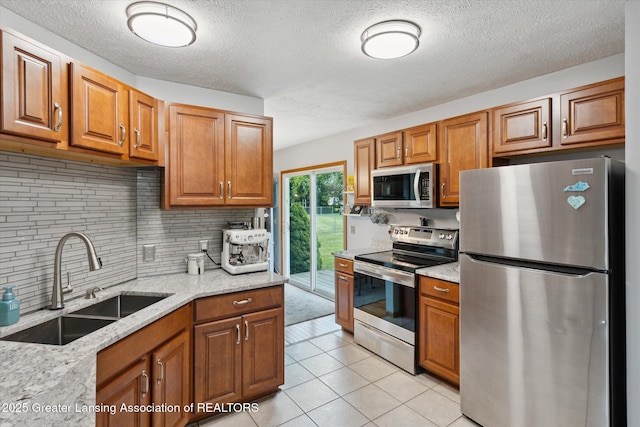 129 Elizabeth Way, Potterville, MI 48876 - kitchen featuring stainless steel appliances, brown cabinets, decorative backsplash, light tile patterned floors, and light stone countertops